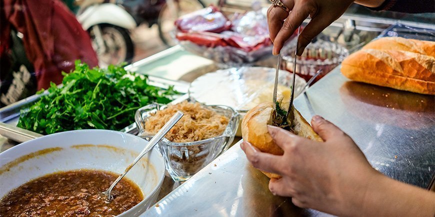 Vrouw maakt een Banh Mi sandwich in Ho Chi Minh City, Vietnam