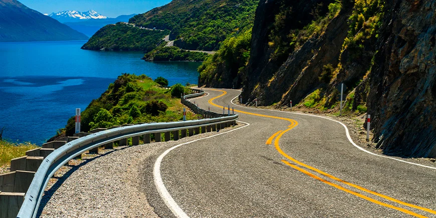 Auto's rijden aan de linkerkant in Nieuw-Zeeland Kronkelige weg in Nieuw-Zeeland