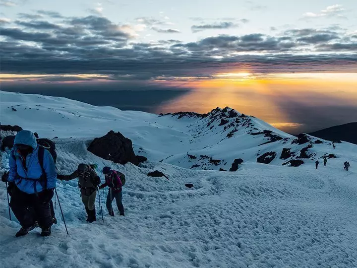 een groep beklimt de kilimanjaro in besneeuwd weer